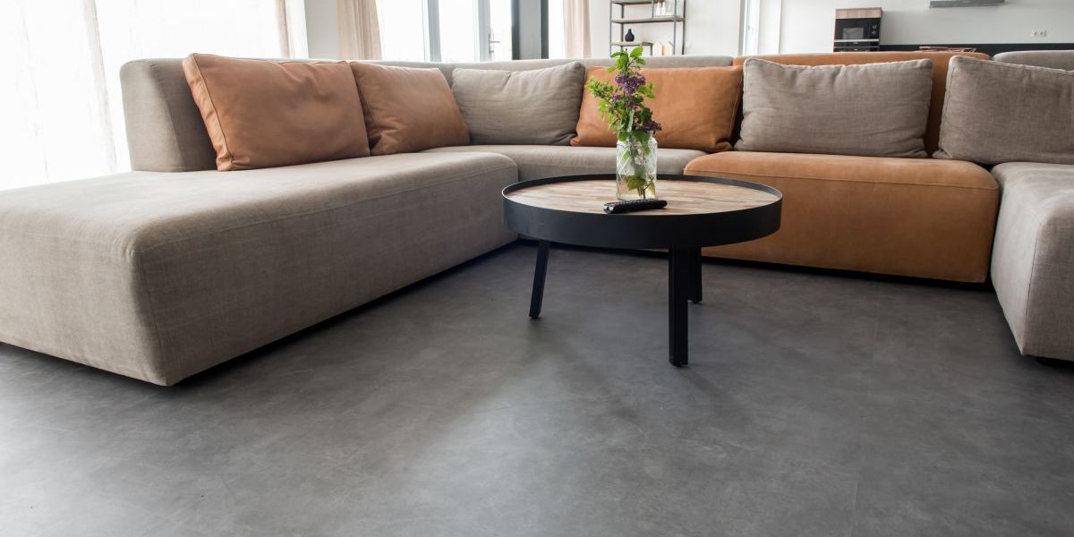 Großes Wohnzimmer mit gemütlicher Sitzgarnitur und Vinylfussboden in Betonoptik.
