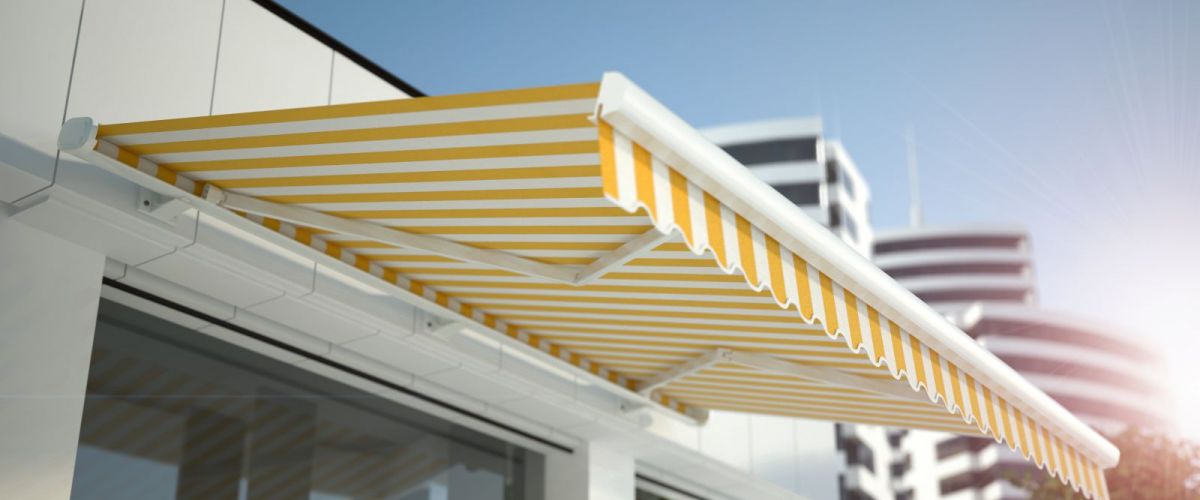 Modernes Haus mit gelb/weiss gestreifter Markise