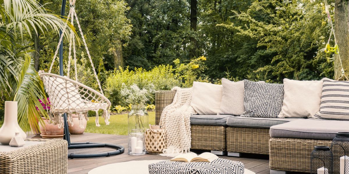 Terrasse mit einem Rattan-Ecksofa, Hängesessel und rundem Teppich