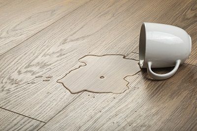 Wasserlache auf Vinylboden durch umgekippte Tasse