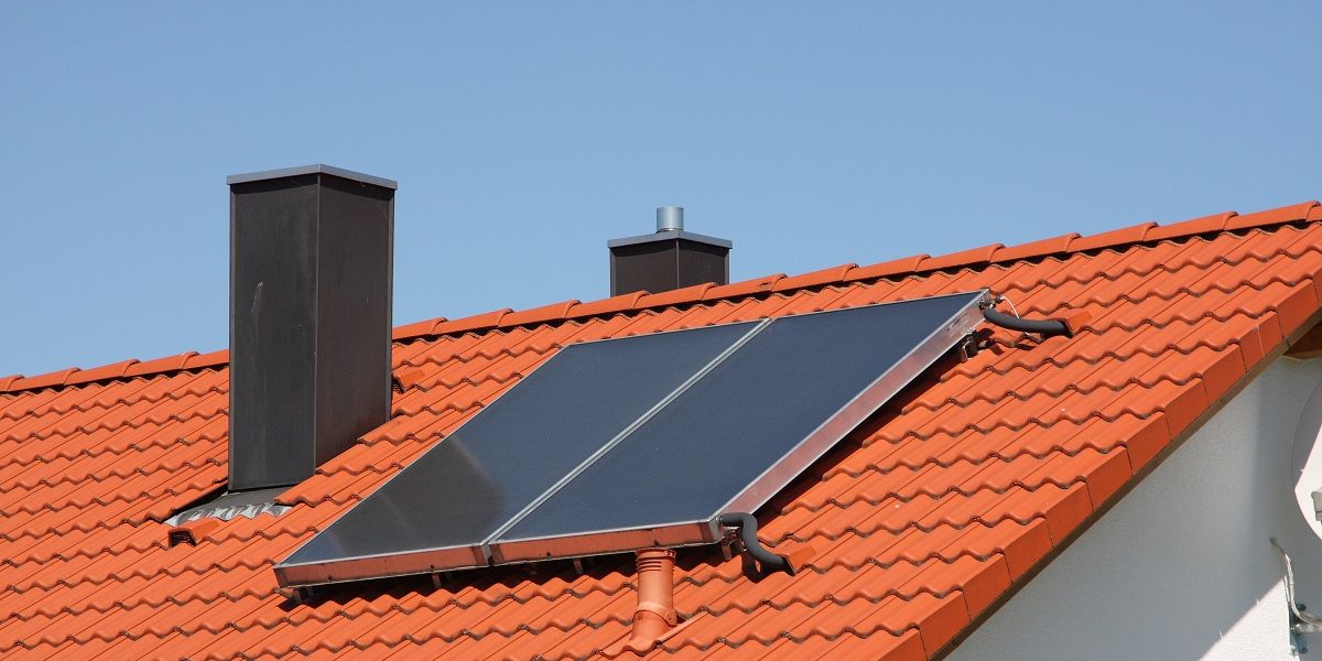 Hausdach mit Solarthermie-Modulen bei strahlendem Sonnenschein