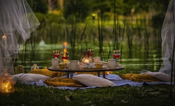 Gemütliches, romantisches Picknick, mit flachem Gartentisch und Kissen auf dem Boden.
