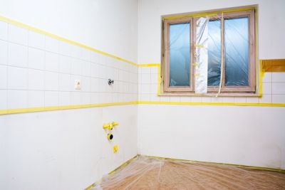 Zum Streichen vorbereitete Küche mit abgeklebtem Fenster und Fliesenspiegel, sowie mit Abdeckfolie geschütztem Fußboden